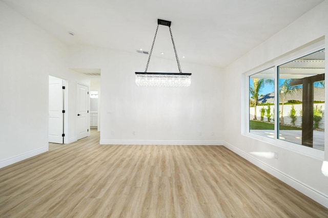 unfurnished room featuring light hardwood / wood-style flooring and a notable chandelier