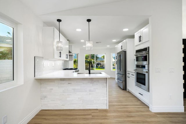 kitchen featuring an inviting chandelier, white cabinetry, kitchen peninsula, stainless steel appliances, and sink