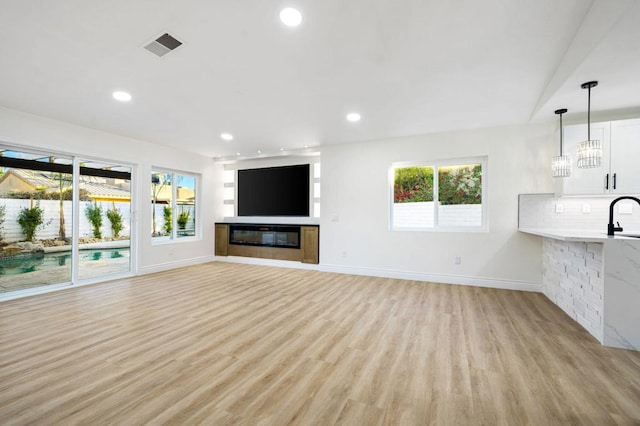 unfurnished living room with light hardwood / wood-style floors and sink