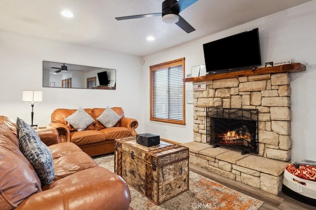 living room featuring ceiling fan, a fireplace, and hardwood / wood-style flooring