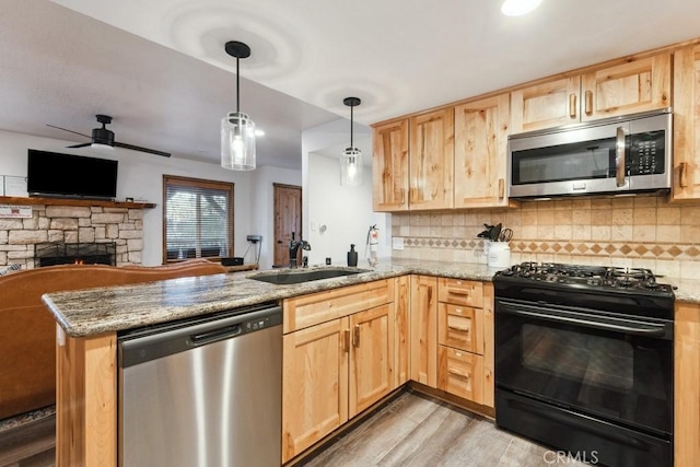 kitchen with kitchen peninsula, stainless steel appliances, decorative backsplash, decorative light fixtures, and sink