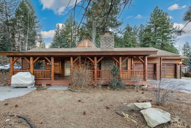 log home with covered porch and a garage