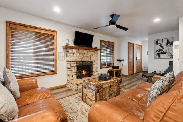 living room with light hardwood / wood-style floors, ceiling fan, and a fireplace