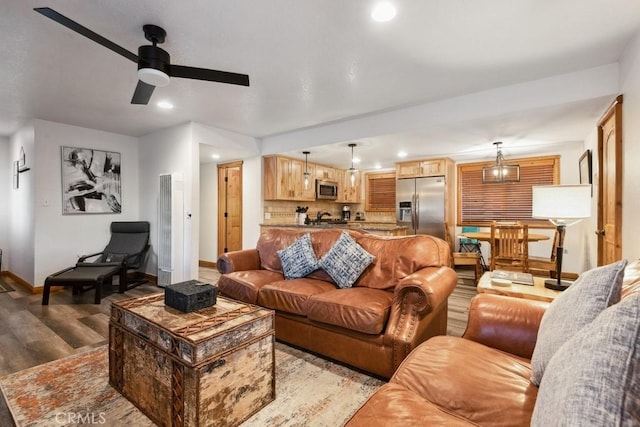 living room with ceiling fan with notable chandelier and light hardwood / wood-style floors