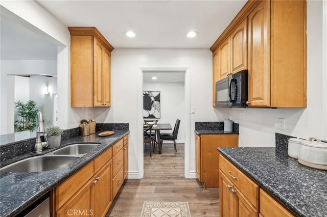 kitchen with dark stone countertops, sink, stainless steel dishwasher, and light hardwood / wood-style flooring