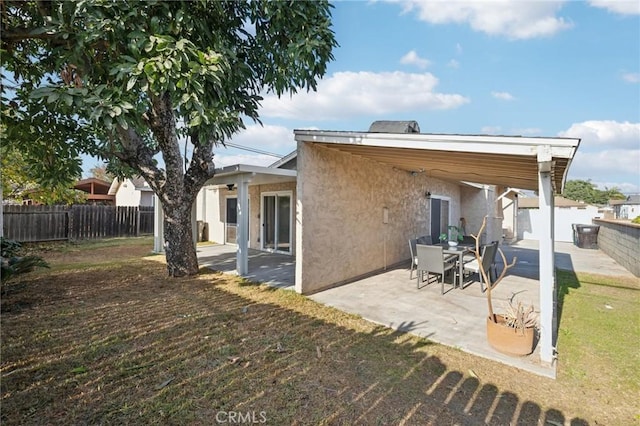 rear view of property with a fenced backyard, a patio, a lawn, and stucco siding