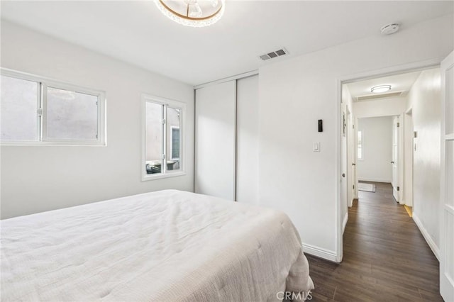 bedroom featuring dark wood-style floors, a closet, visible vents, and baseboards