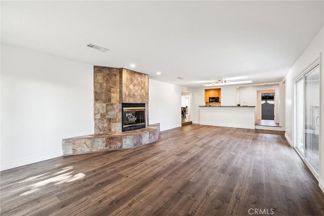 unfurnished living room featuring baseboards, visible vents, dark wood finished floors, a fireplace, and recessed lighting