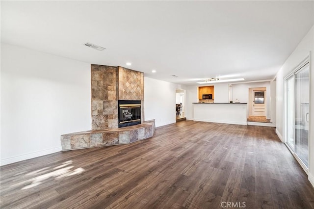 unfurnished living room featuring visible vents, a fireplace, baseboards, and wood finished floors