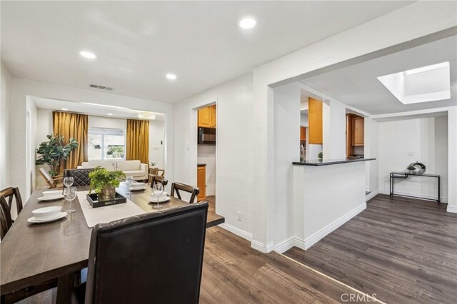 dining area featuring dark hardwood / wood-style floors and a skylight