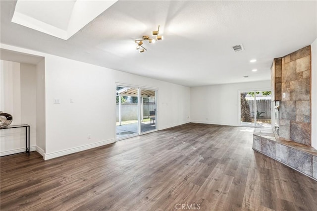 unfurnished living room with wood finished floors, visible vents, and baseboards