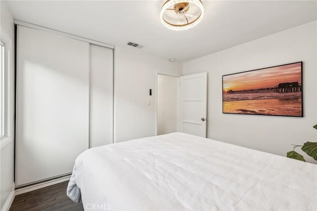 bedroom with a closet, dark wood finished floors, and visible vents