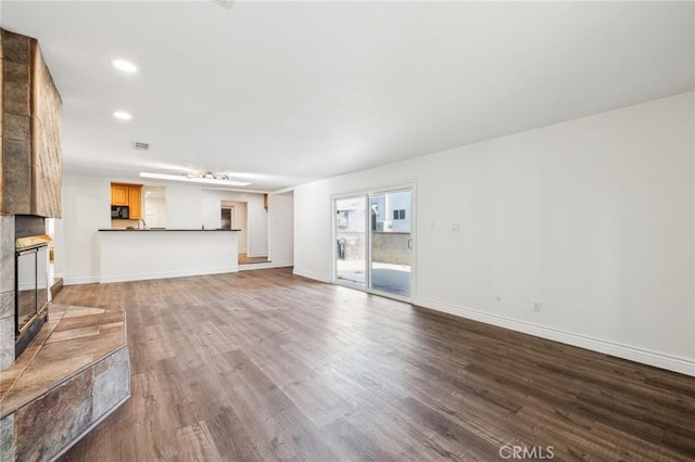 unfurnished living room with recessed lighting, visible vents, a large fireplace, wood finished floors, and baseboards