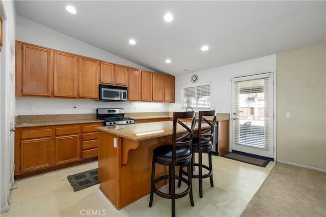 kitchen featuring a breakfast bar, a center island, stainless steel appliances, and vaulted ceiling