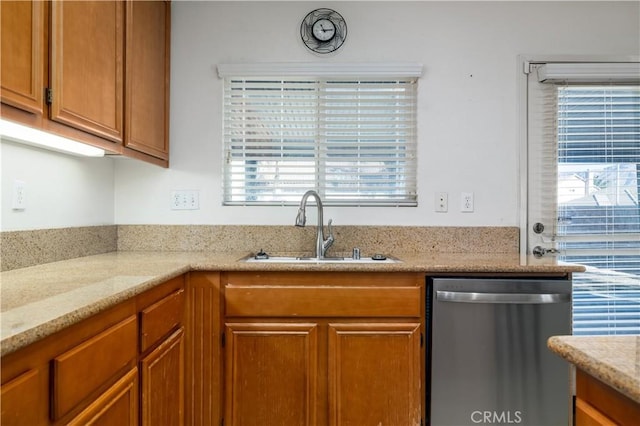 kitchen with light stone countertops, sink, and stainless steel dishwasher