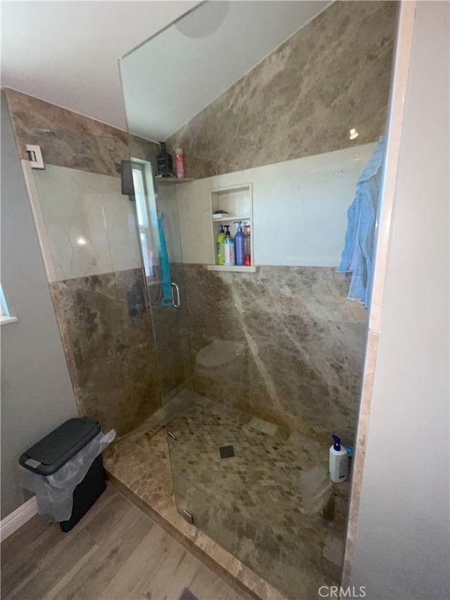 bathroom with a shower with shower door and hardwood / wood-style floors