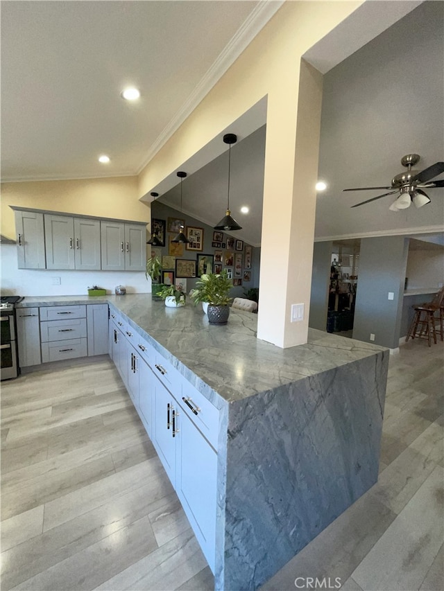 kitchen featuring lofted ceiling, ceiling fan, hanging light fixtures, kitchen peninsula, and light stone counters