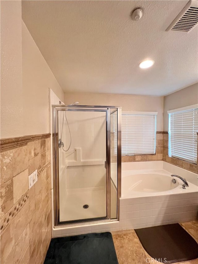 bathroom featuring separate shower and tub, tile walls, tile patterned floors, and a textured ceiling