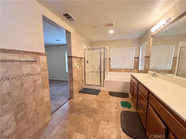 bathroom with vanity, tile walls, plus walk in shower, and a textured ceiling