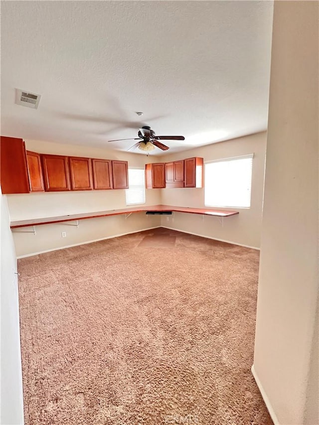 unfurnished living room featuring ceiling fan, carpet, and a textured ceiling