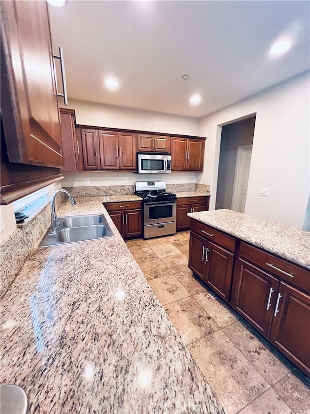 kitchen with light stone countertops, sink, and stainless steel appliances