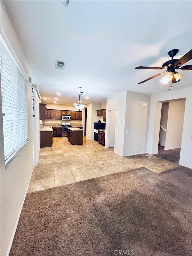 unfurnished living room featuring ceiling fan and light carpet