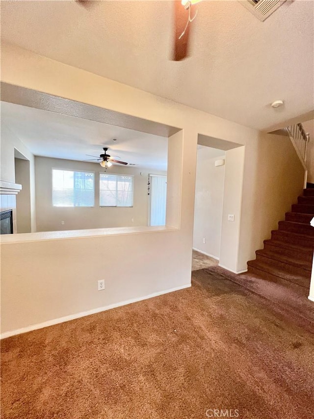 unfurnished room with a textured ceiling, ceiling fan, and carpet