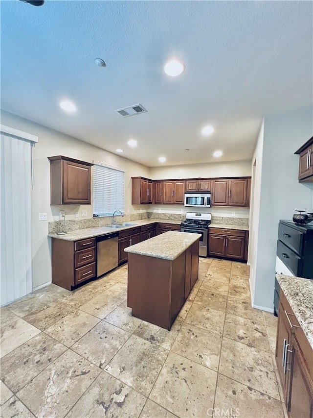 kitchen featuring dark brown cabinets, sink, stainless steel appliances, and a kitchen island