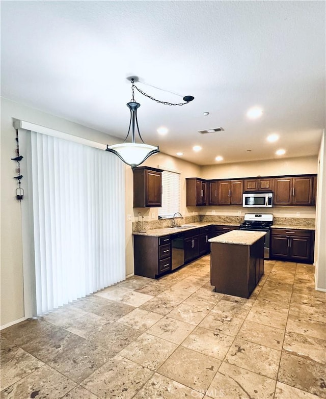 kitchen featuring decorative light fixtures, a center island, sink, stainless steel appliances, and dark brown cabinets