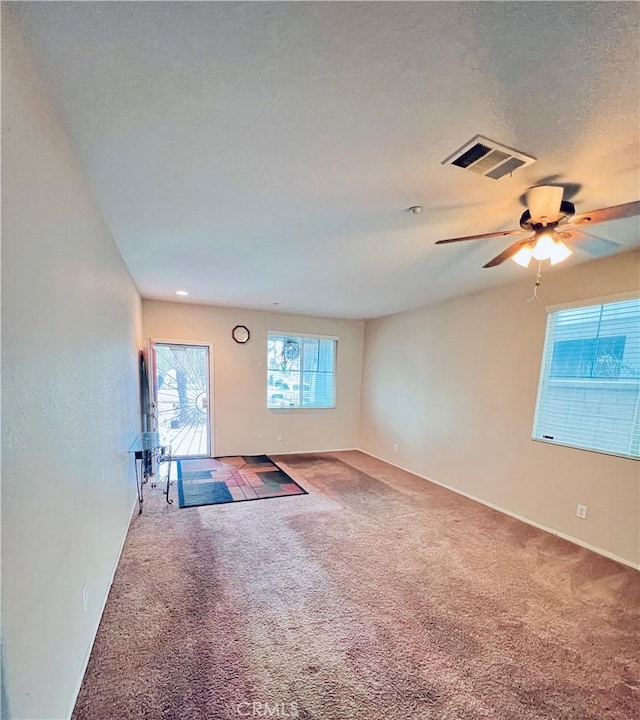 unfurnished room with carpet, ceiling fan, and a textured ceiling