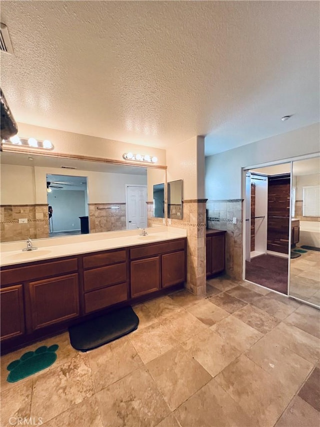 bathroom with vanity, tile walls, and a textured ceiling