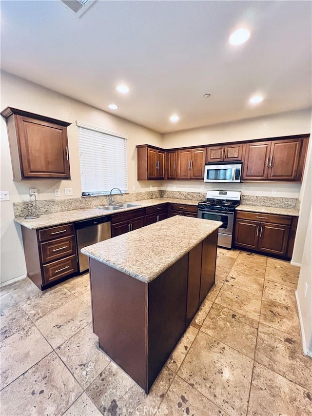 kitchen with a center island, stainless steel appliances, sink, light stone counters, and dark brown cabinets