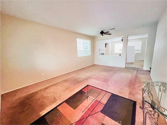 unfurnished living room with ceiling fan and carpet