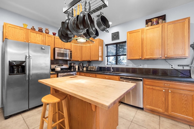 kitchen featuring light tile patterned flooring, sink, stainless steel appliances, and wood counters