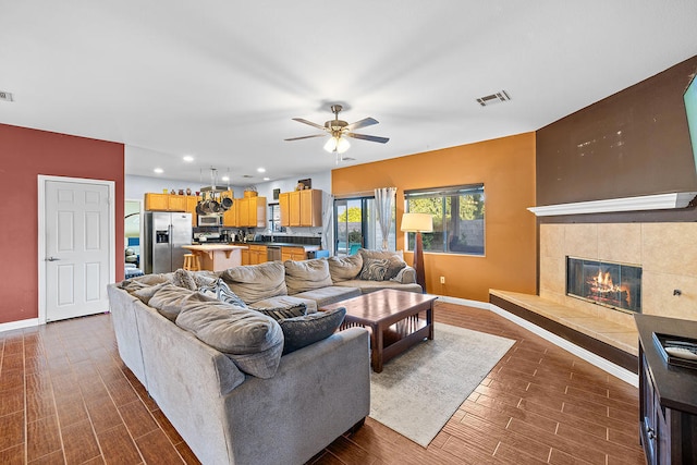 living room featuring ceiling fan and a tile fireplace