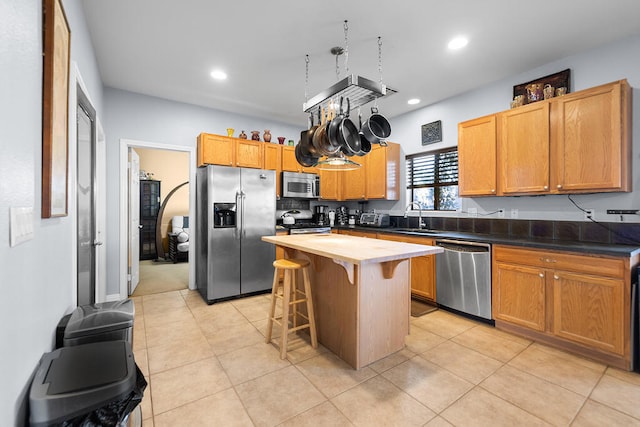 kitchen featuring a kitchen island, stainless steel appliances, sink, a breakfast bar, and light tile patterned floors