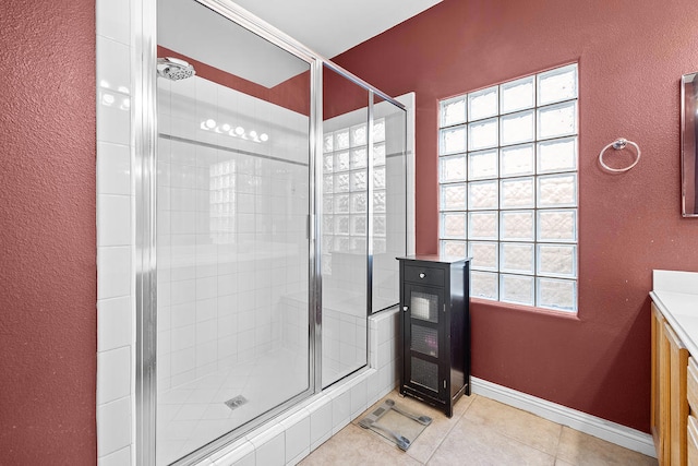 bathroom with tile patterned floors, a shower with door, vanity, and a healthy amount of sunlight