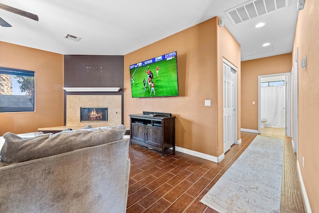 living room with ceiling fan and a fireplace