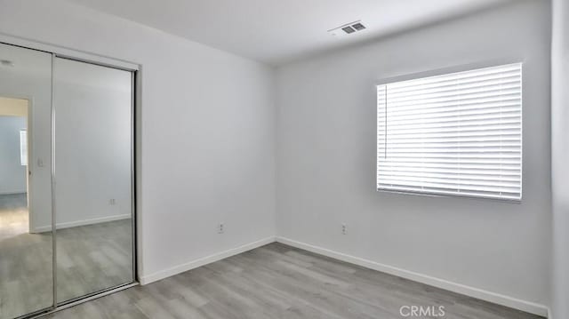 unfurnished bedroom with a closet and light hardwood / wood-style flooring