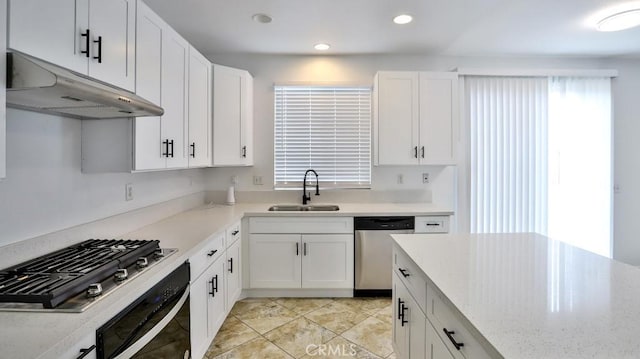 kitchen with white cabinets, appliances with stainless steel finishes, sink, and light stone counters