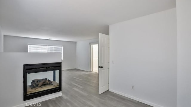 unfurnished living room with a multi sided fireplace and light hardwood / wood-style floors