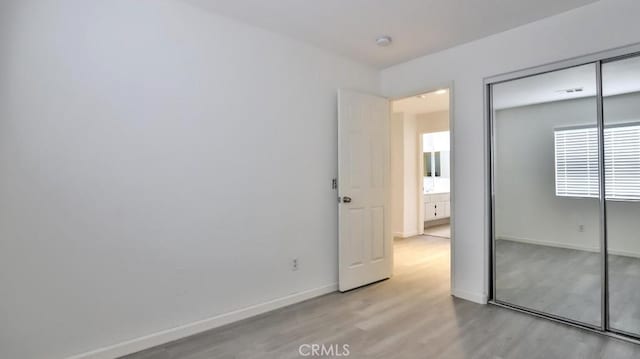 unfurnished bedroom with a closet and light wood-type flooring