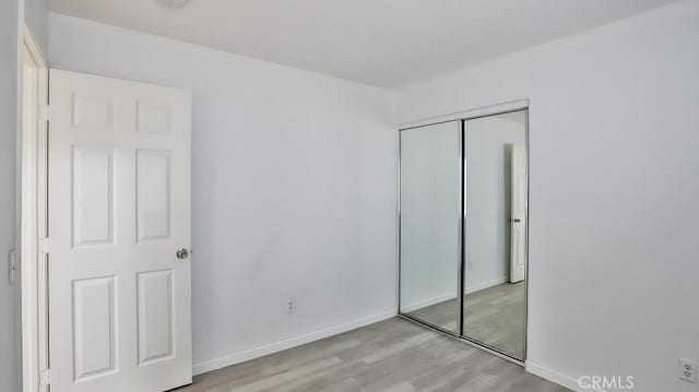 unfurnished bedroom with light wood-type flooring and a closet