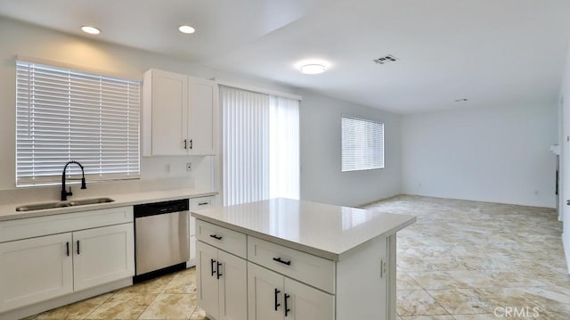 kitchen with sink, white cabinets, stainless steel dishwasher, and a kitchen island