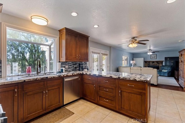 kitchen featuring kitchen peninsula, decorative backsplash, dishwasher, light stone counters, and sink