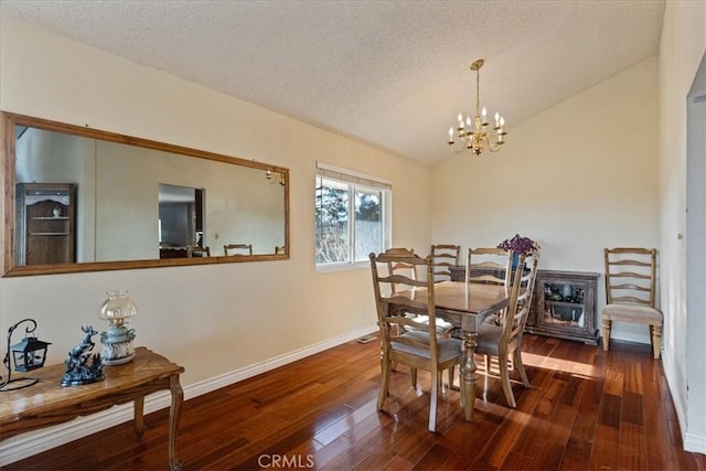 dining space featuring dark wood-type flooring, a textured ceiling, and an inviting chandelier