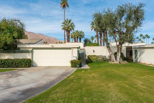 ranch-style home featuring a mountain view, a front lawn, and a garage