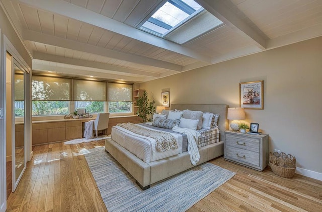 bedroom with light wood-type flooring, a skylight, and beamed ceiling