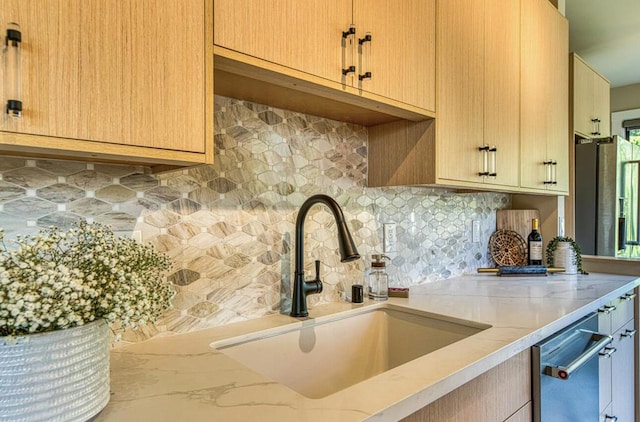 kitchen featuring tasteful backsplash, light brown cabinets, sink, and stainless steel dishwasher