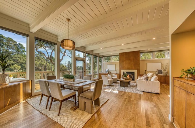 sunroom featuring plenty of natural light, beamed ceiling, and a fireplace